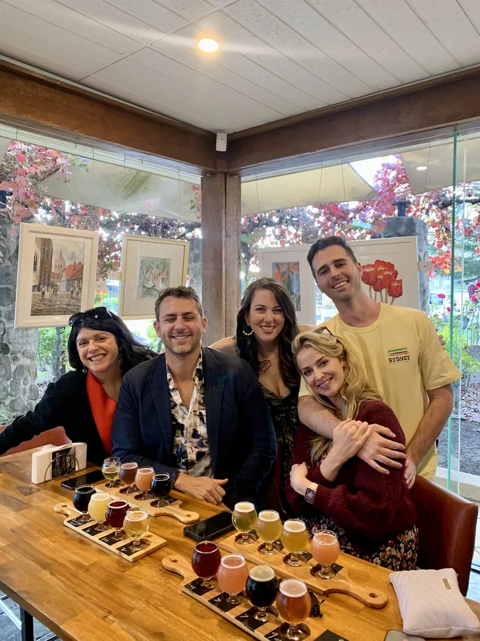 Tour guests smiling together behind a row of tasting paddles